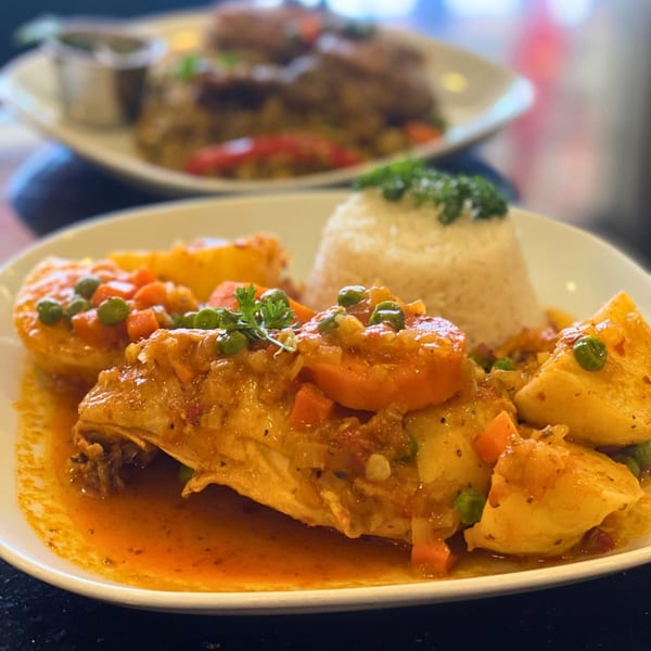 Peruvian Aji de Gallina with rice, potatoes, carrots, and peas, served on a white plate.